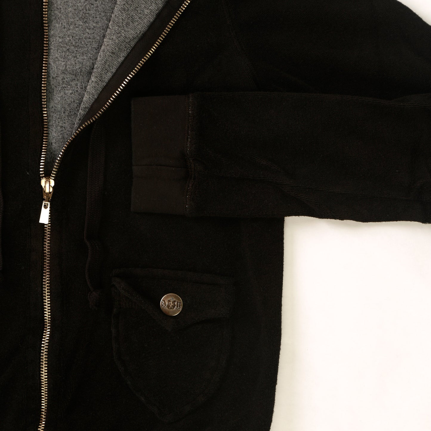 close-up of women's black velvety fabric jacket with drawstring hood and two front pockets with metal buttoned flaps with cuffed sleeves and hemming and full-length metal zipper