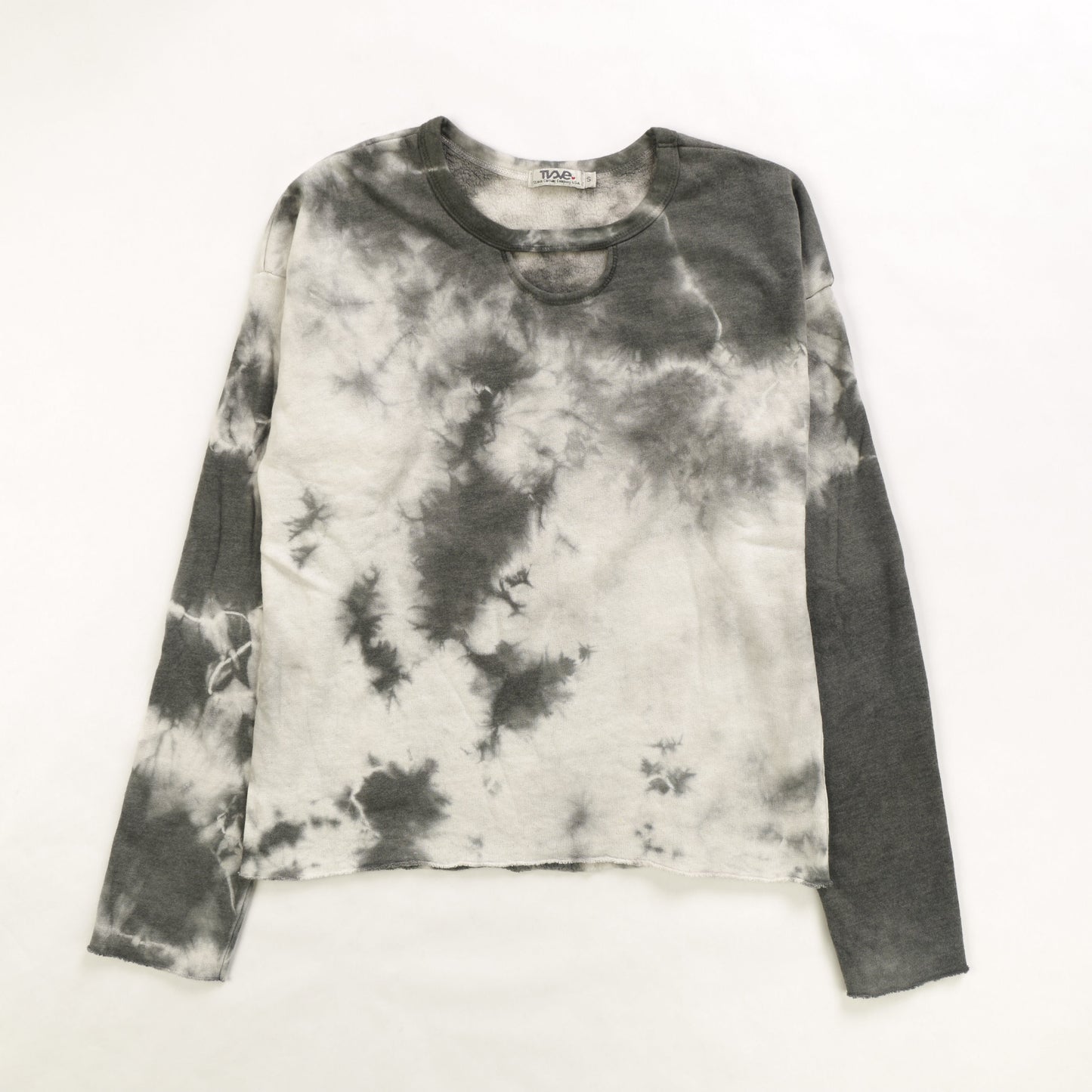 women's looser-fit long-sleeved shirt with raw edges at the sleeves and bottom hem and a half-circle keyhole cutout right underneath the neckline with black tie-dye splotches on white colored fabric